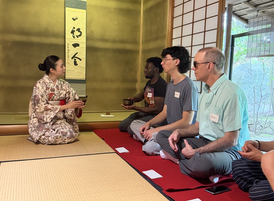 tea ceremony CS students being instructed by a woman in kimono on proper etiquette in a traditional tea ceremony.